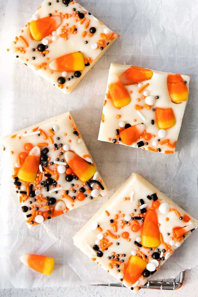 Dark chocolate fudge squares swirled with orange and green icing, topped with candy corn on a festive platter